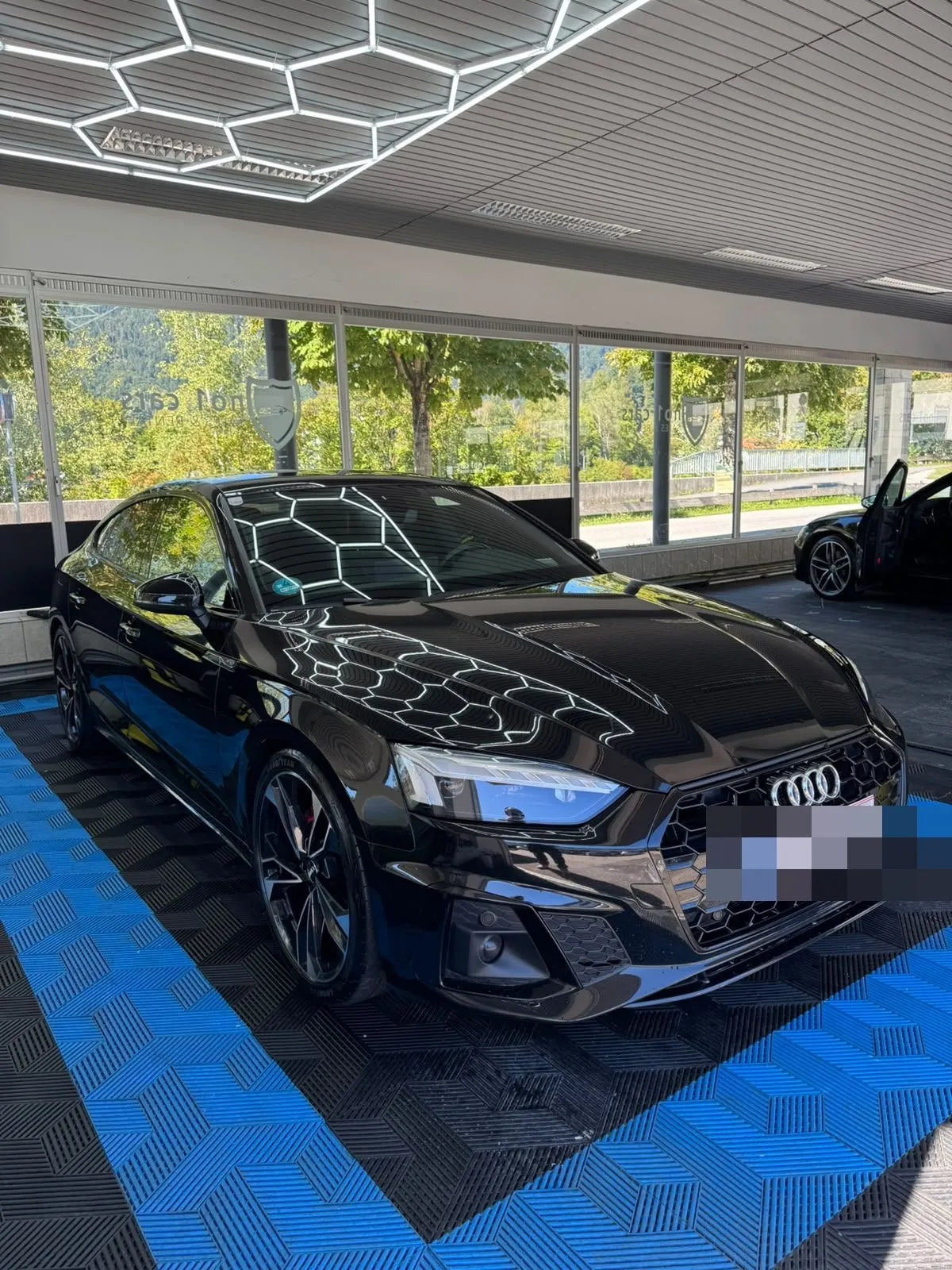 Audi A5 Sportback in der Halle von Saff Car Lounge in Kufstein nach der Aufbereitung, Hexagon-Leuchten spiegeln sich im Lack