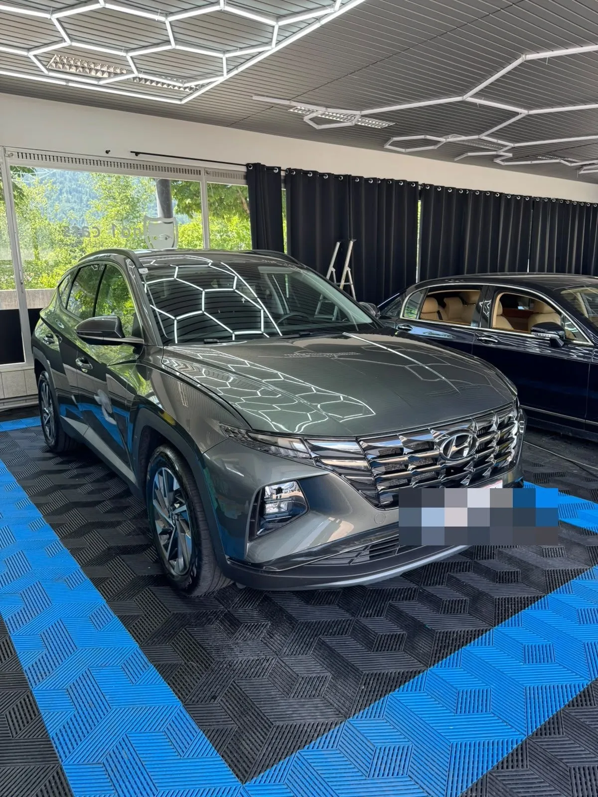 Hyundai Tucson in der Halle von Saff Car Lounge in Kufstein nach der Aufbereitung, Hexagon-Leuchten spiegeln sich im Lack