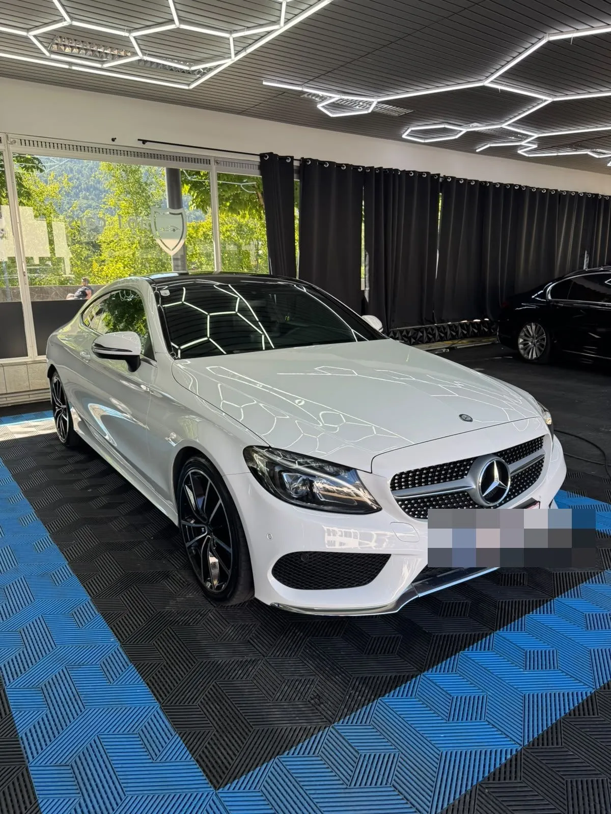 Mercedes C-Klasse Coupé in der Halle von Saff Car Lounge in Kufstein nach der Aufbereitung, Hexagon-Leuchten spiegeln sich im Lack