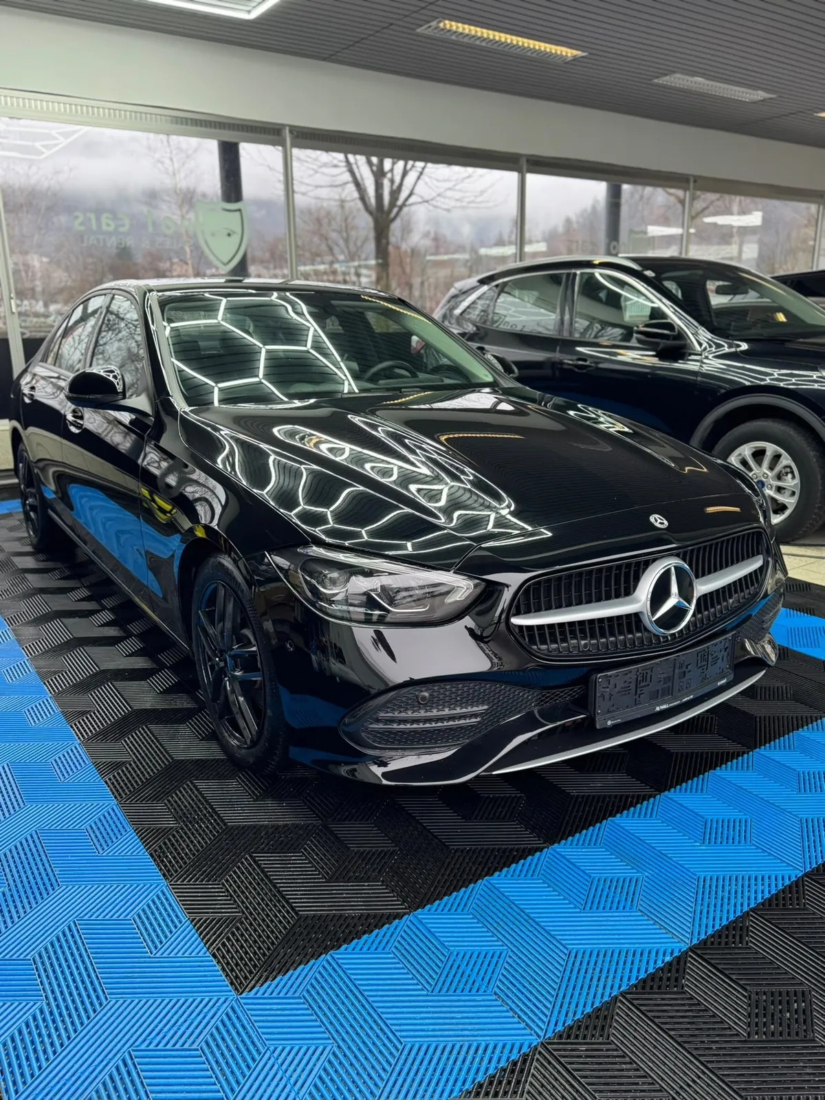 Mercedes C-Klasse in der Halle von Saff Car Lounge in Kufstein nach der Aufbereitung, Hexagon-Leuchten spiegeln sich im Lack