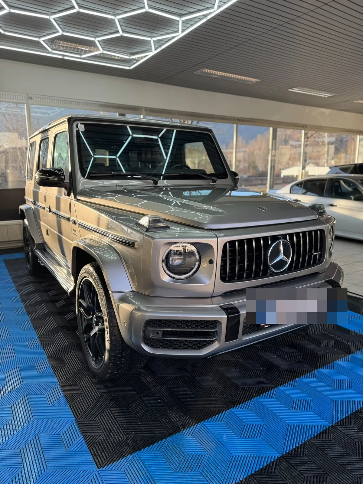Mercedes G-Klasse in der Halle von Saff Car Lounge in Kufstein nach der Aufbereitung, Hexagon-Leuchten spiegeln sich im Lack