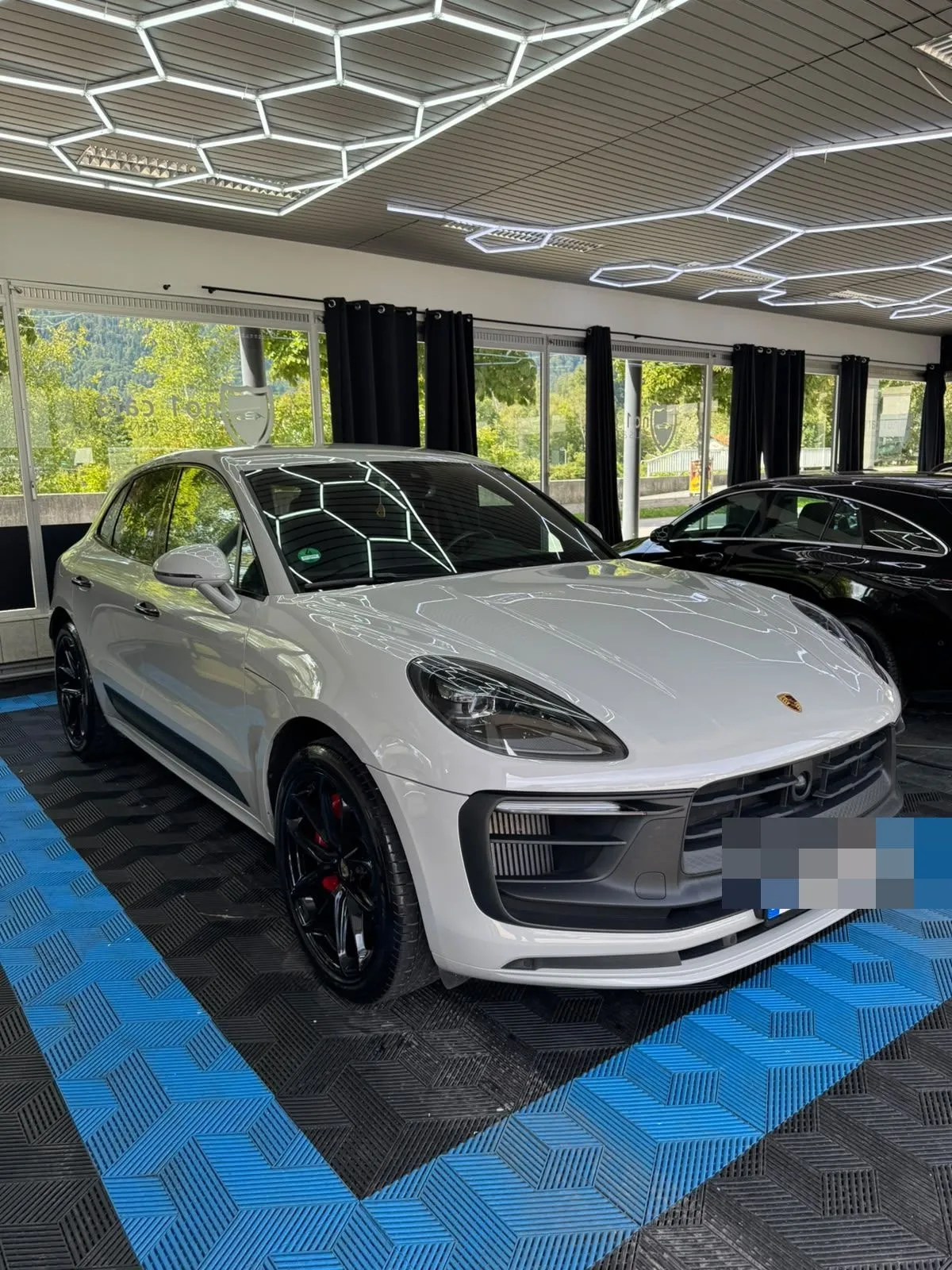Porsche Macan in der Halle von Saff Car Lounge in Kufstein nach der Aufbereitung, Hexagon-Leuchten spiegeln sich im Lack