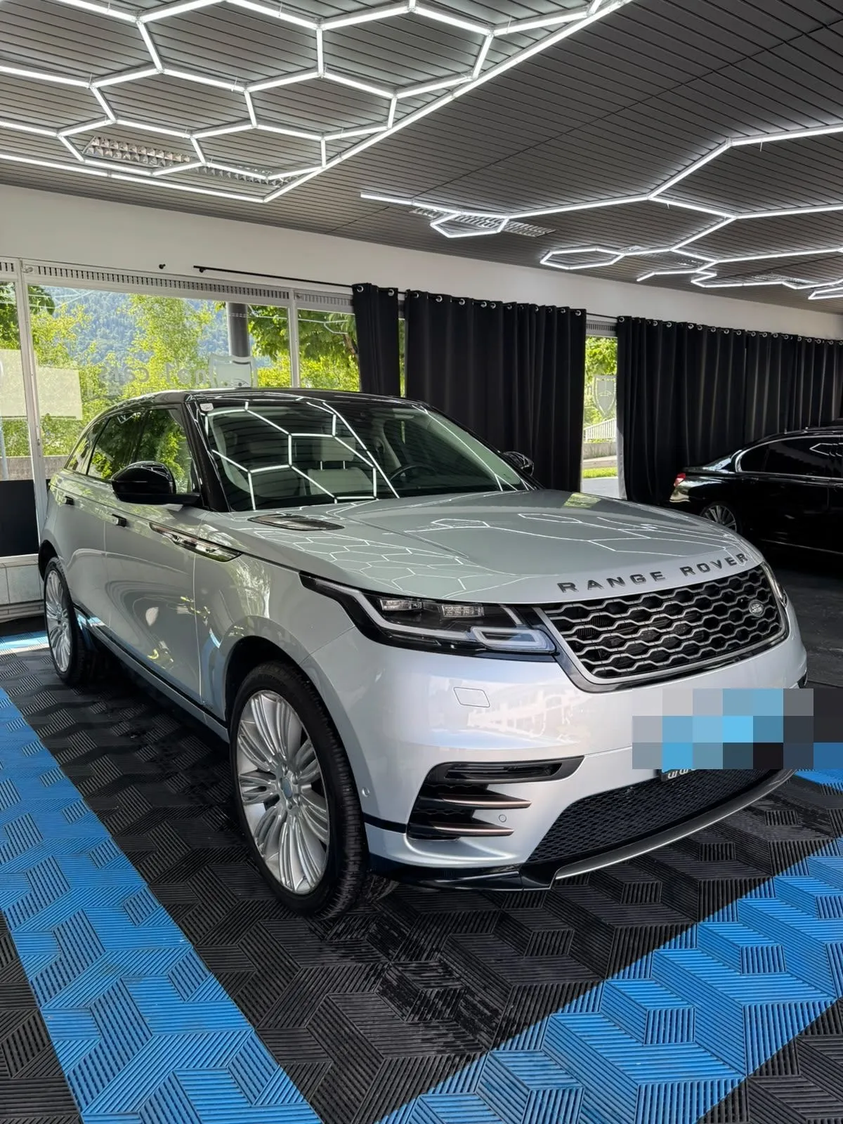 Range Rover Velar in der Halle von Saff Car Lounge in Kufstein nach der Aufbereitung, Hexagon-Leuchten spiegeln sich im Lack