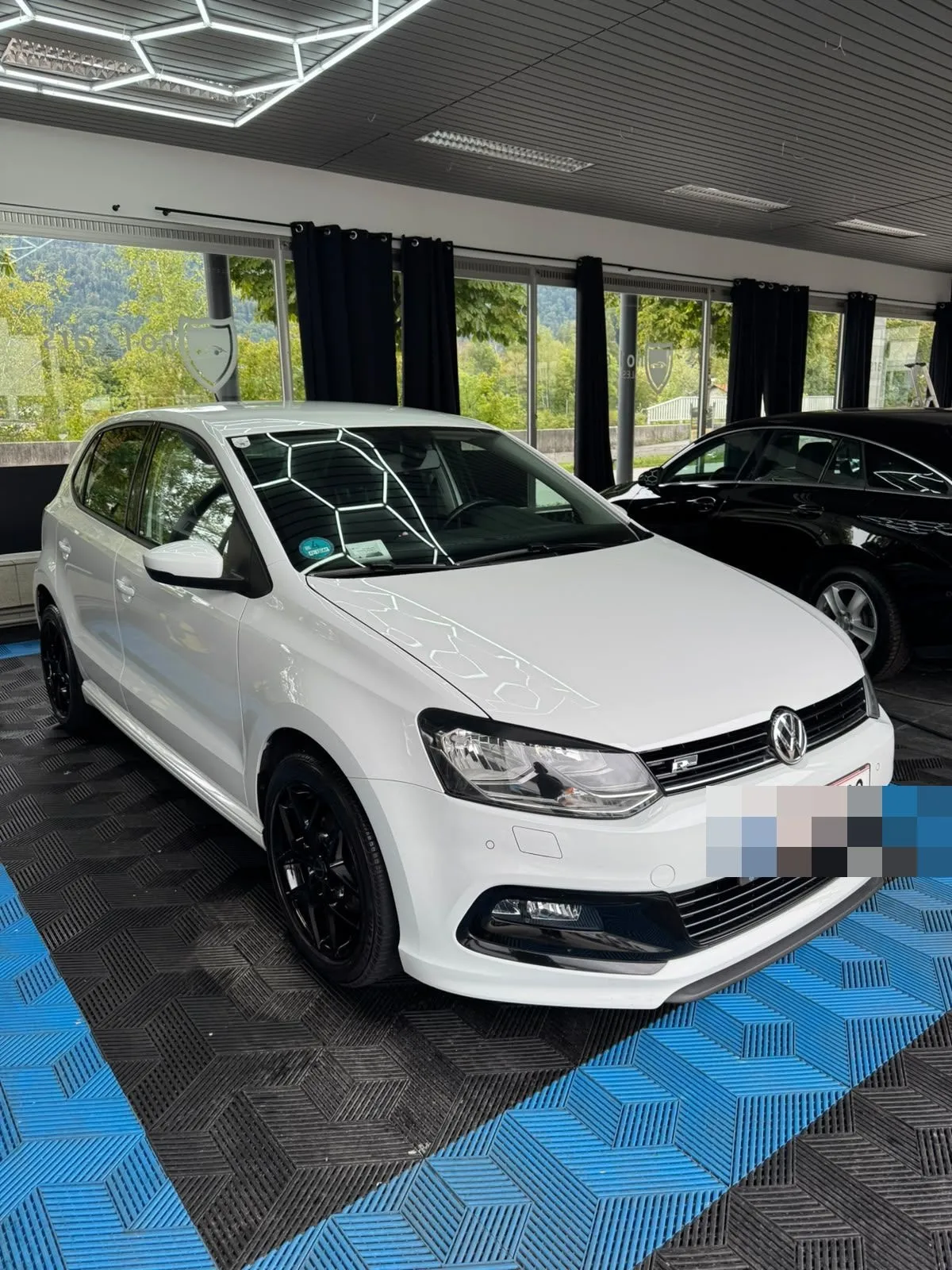 VW Polo R-Line in der Halle von Saff Car Lounge in Kufstein nach der Aufbereitung, Hexagon-Leuchten spiegeln sich im Lack