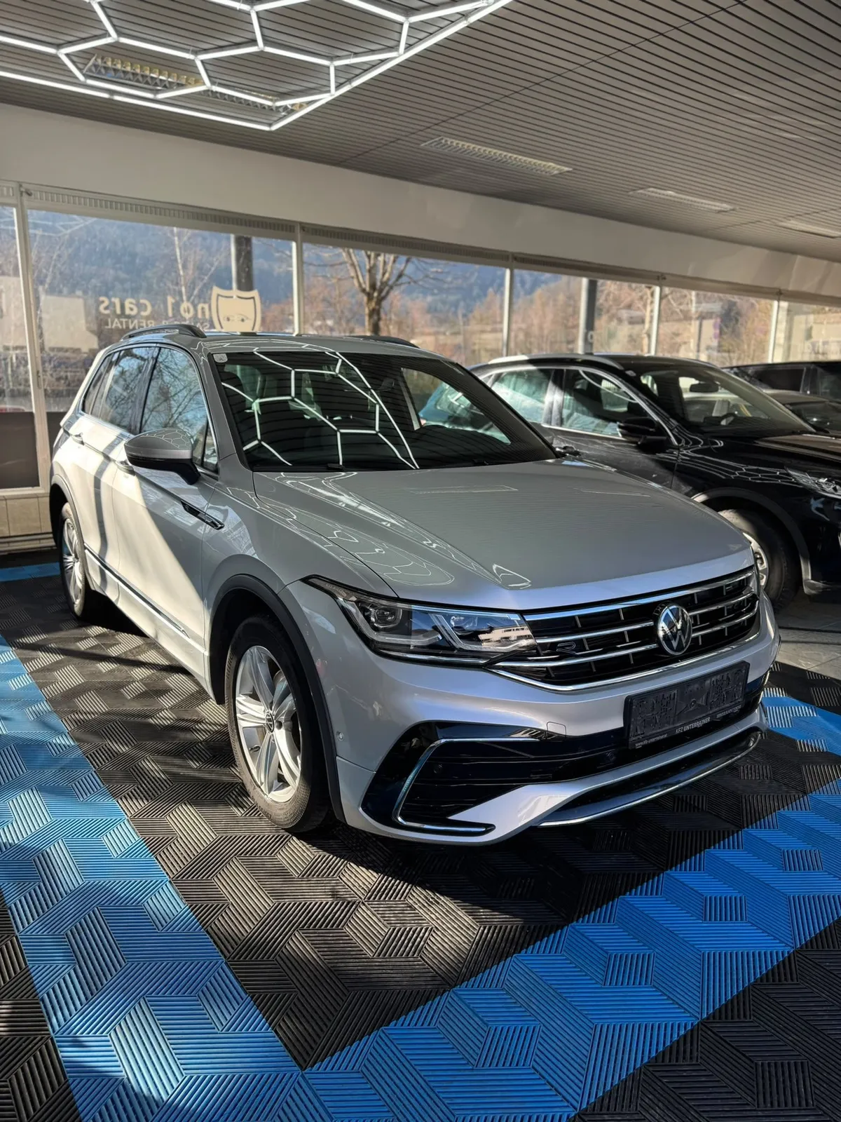 VW Tiguan in der Halle von Saff Car Lounge in Kufstein nach der Aufbereitung, Hexagon-Leuchten spiegeln sich im Lack